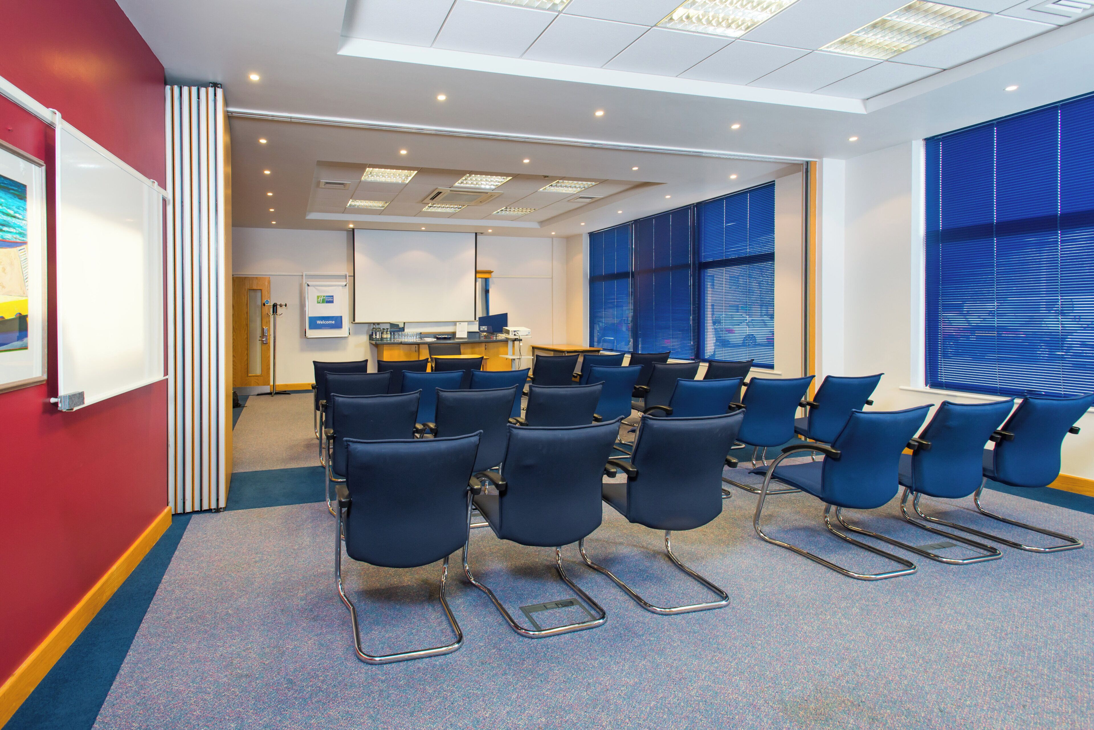 A conference room with rows of chairs, a whiteboard, and a reception desk.