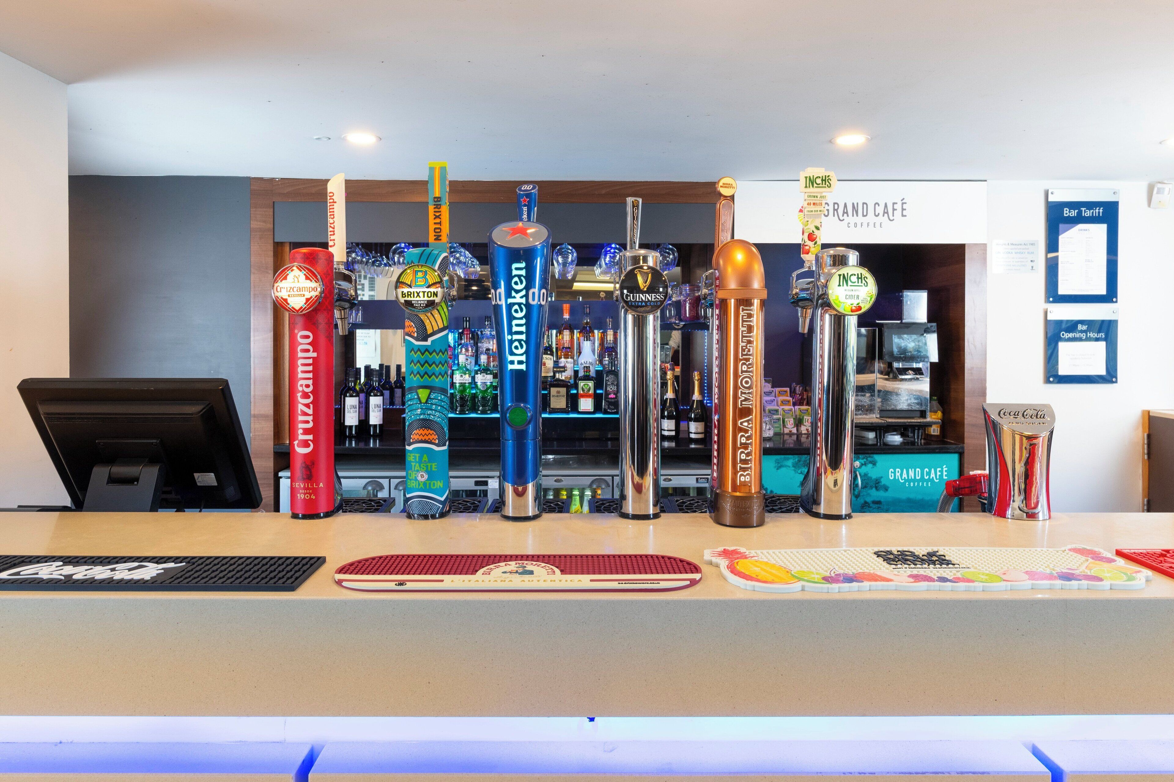 Zona de bar con diversas griferías de cerveza, incluyendo marcas como Heineken, Guinness y Corona.