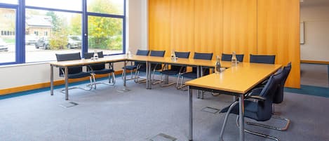 A conference room with a long table, chairs, and a large window.
