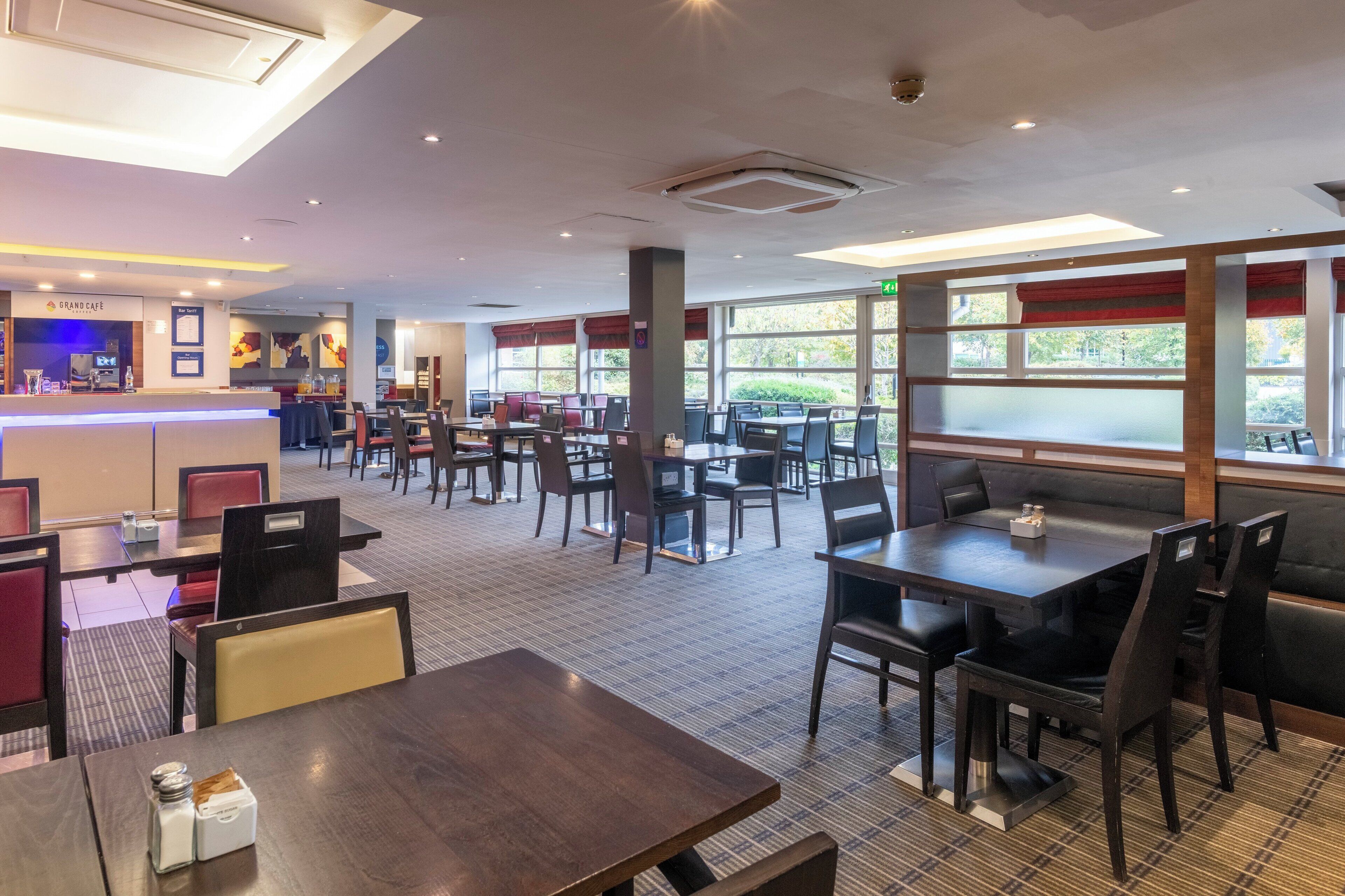 A spacious restaurant with multiple dining areas, including booths and tables, and a counter for ordering.