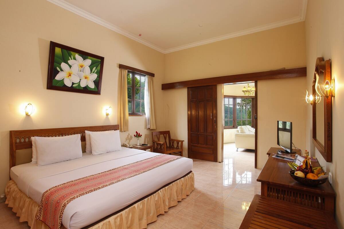 A hotel room with a large bed, a desk with a computer, a TV, and a fruit bowl.