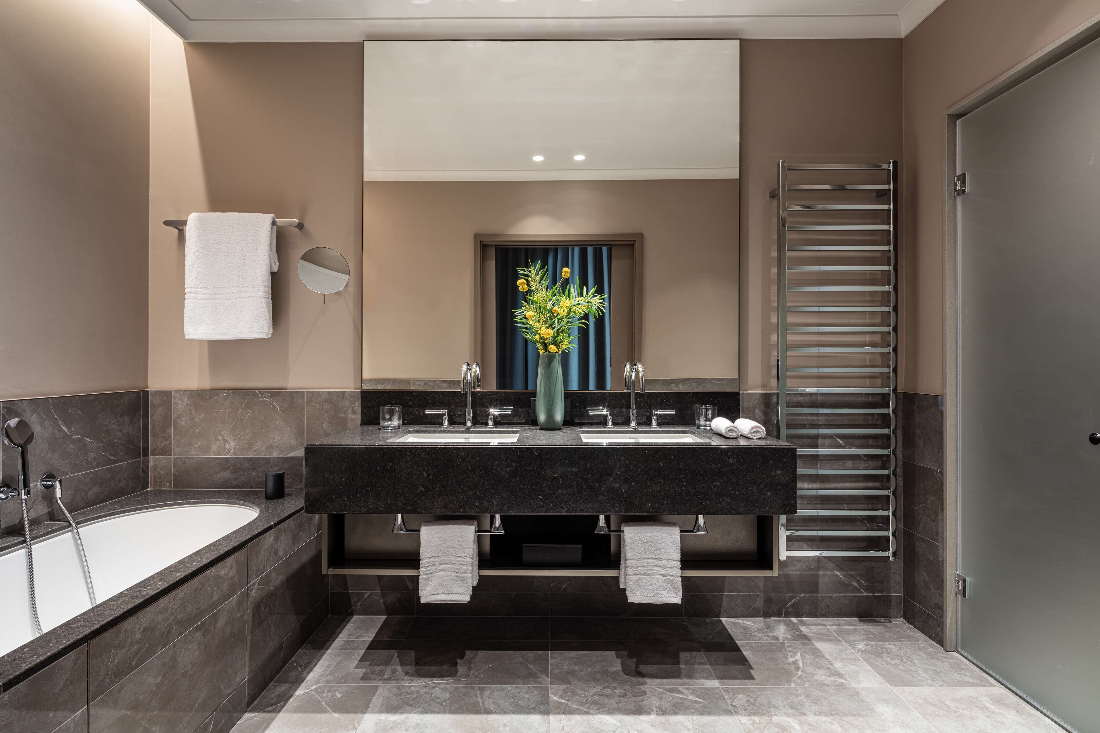 Une salle de bain moderne avec une grande baignoire, deux lavabos, un miroir et un porte-serviettes.