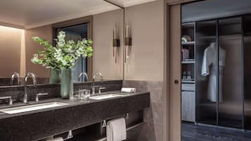 Un baño moderno con tocador doble lavamanos, un espejo grande y una planta en maceta.