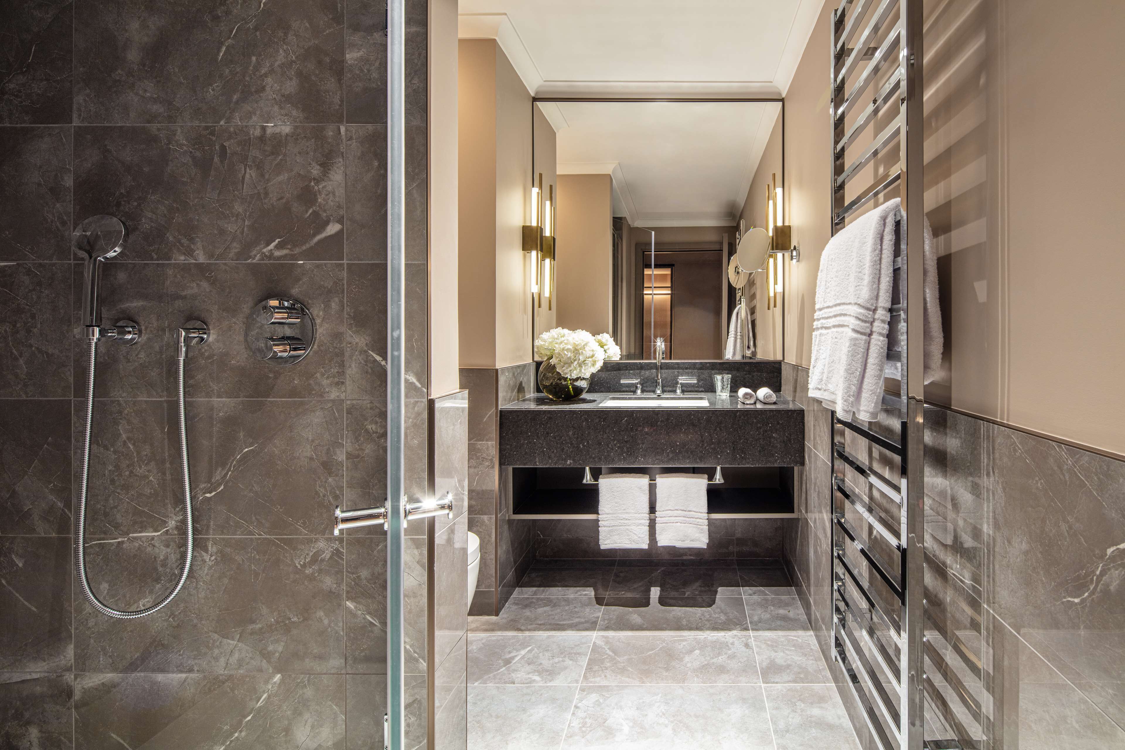 A modern bathroom with a glass shower enclosure, a vanity with a mirror, and a towel rack.