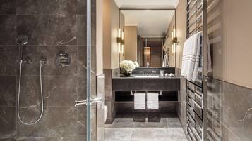 A modern bathroom with a glass shower enclosure, a vanity with a mirror, and a towel rack.