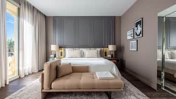 Un dormitorio con una cama grande, un sofá, una mesita de noche con lámparas y un espejo.