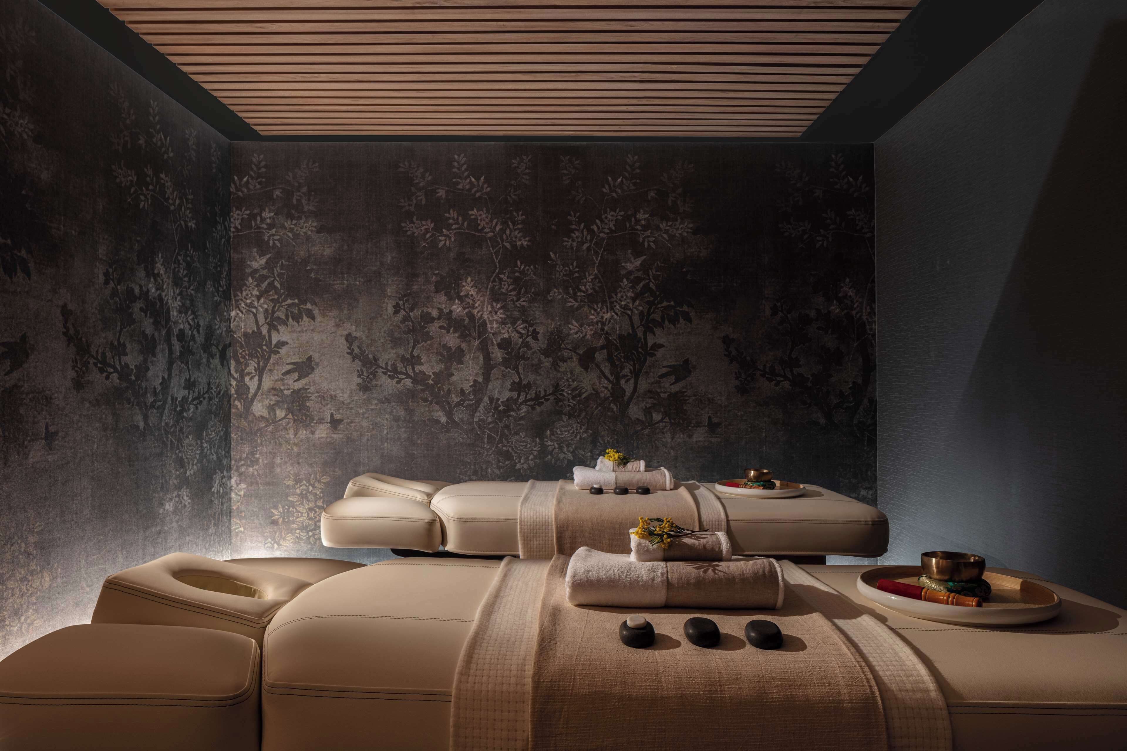 Habitación de spa con camilla de masaje, toallas y un cuenco.