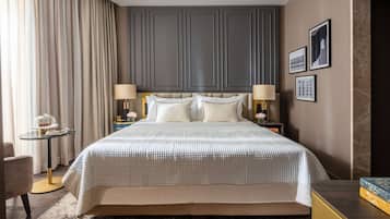 A hotel room with a large bed, two bedside tables with lamps, a small round table with a decorative item, and a chair.