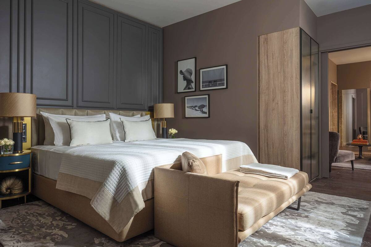 A modern bedroom with a large bed, bedside tables, a chair, and a wardrobe.