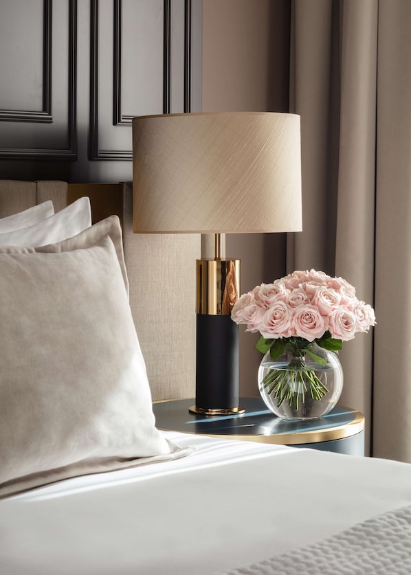 A bed with a white comforter, a black and gold lamp, and a vase with pink roses on a bedside table. - Anantara Plaza Nice Hotel - A Leading Hotel of the World (Nice)