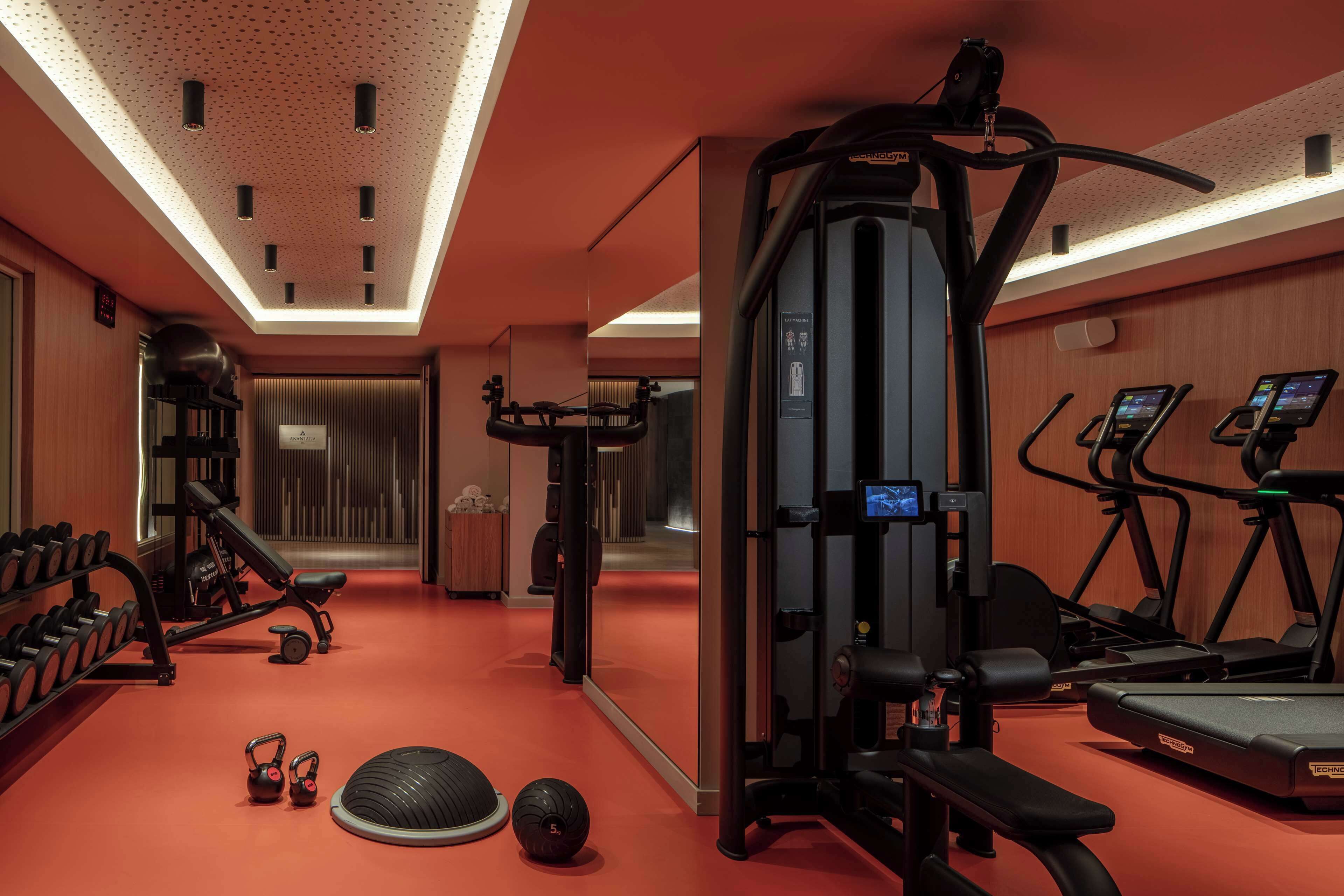 A gym with cardio machines, free weights, and a mirrored wall.