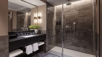 A modern bathroom with a glass-enclosed shower, a large mirror, and a dark marble countertop.