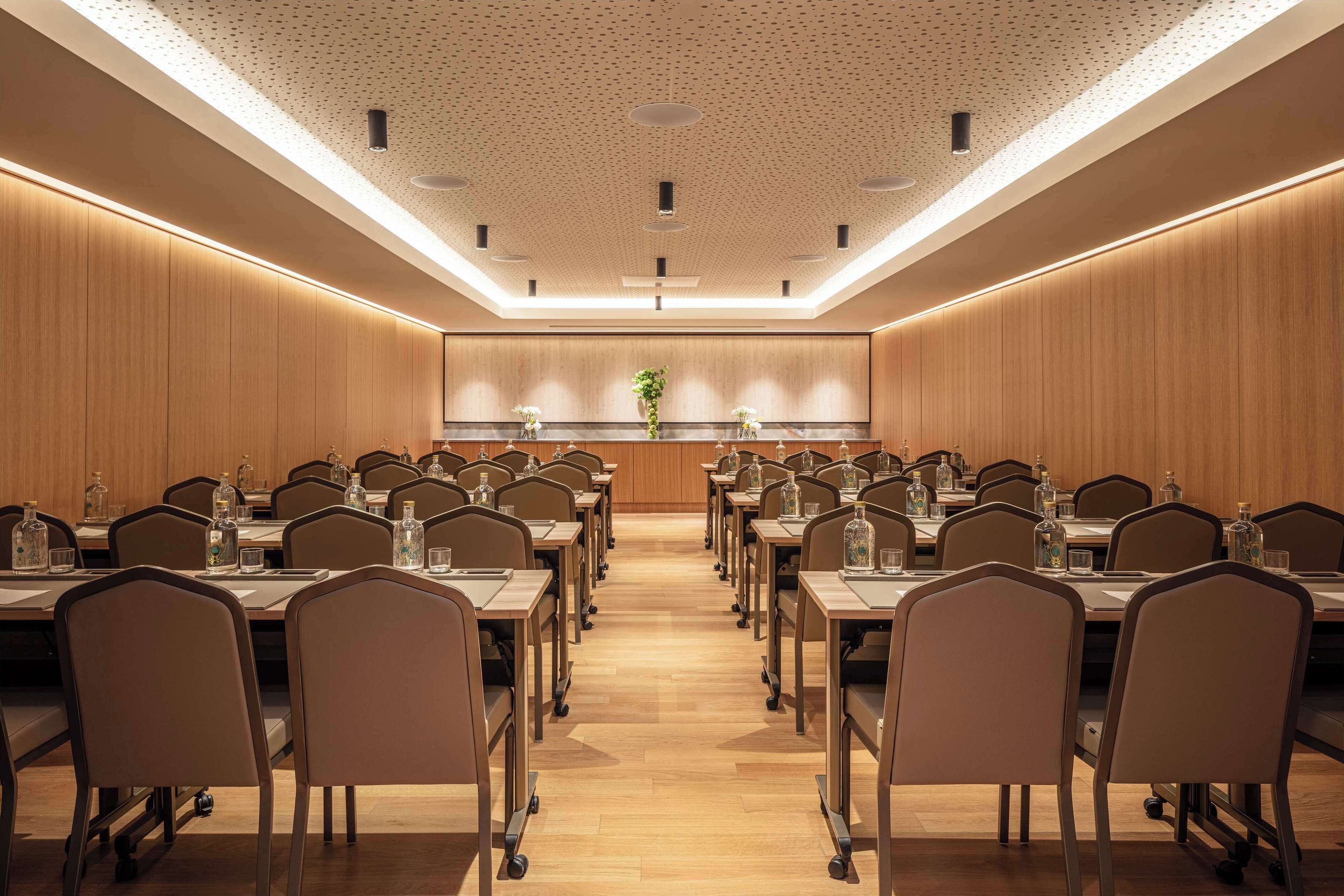 A conference room with a long table, chairs, and a central plant.