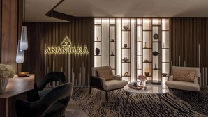 Una sala de estar moderna con un sofá, sillas, una mesa de centro y una pared decorativa con estanterías.