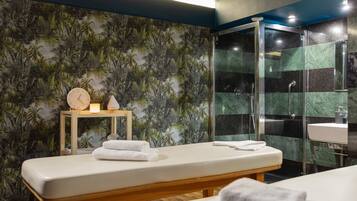 A modern bathroom with a wooden bench, a glass shower enclosure, and a wall with a tropical leaf pattern.