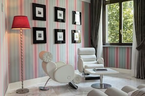 A modern living room with a striped wall, a red floor lamp, a white sofa, and framed pictures.