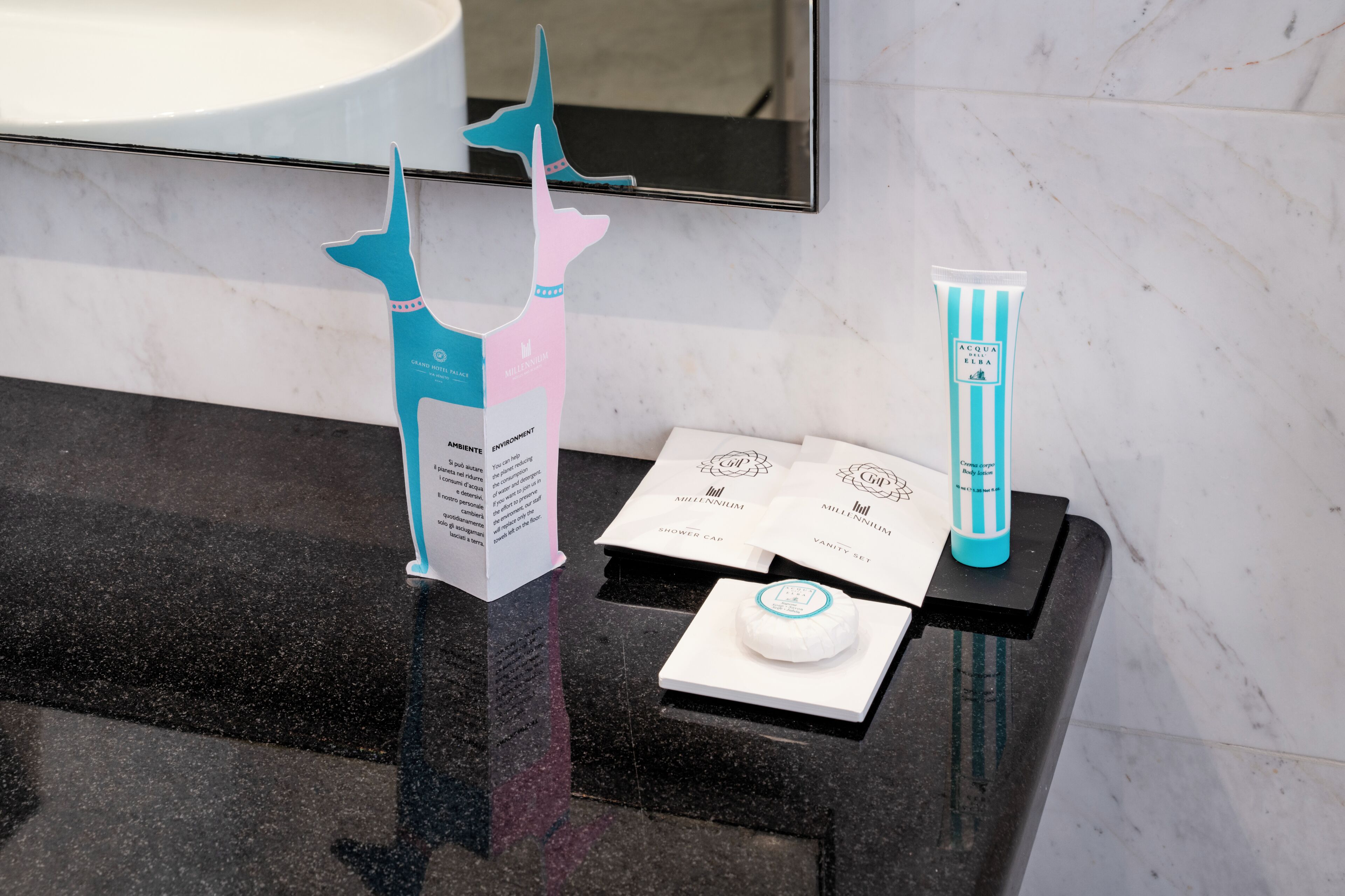 A bathroom counter with a mirror, a sink, and toiletries.