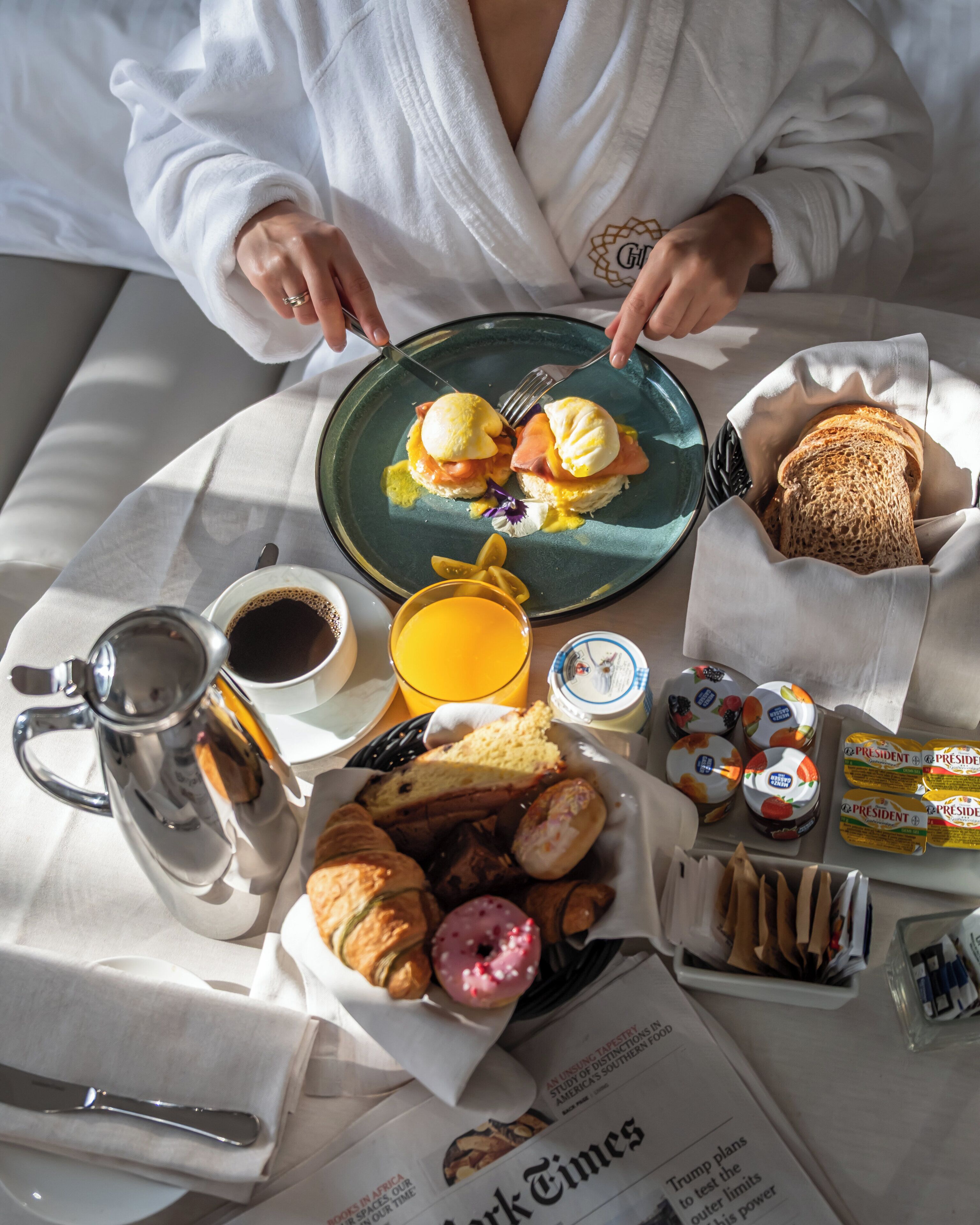 En morgenmadsopsætning med æg, ristet brød, bagværk og kaffe på et bord.