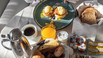 Impostazione per la colazione con uova, pane tostato, pasticcini e caffè su un tavolo.