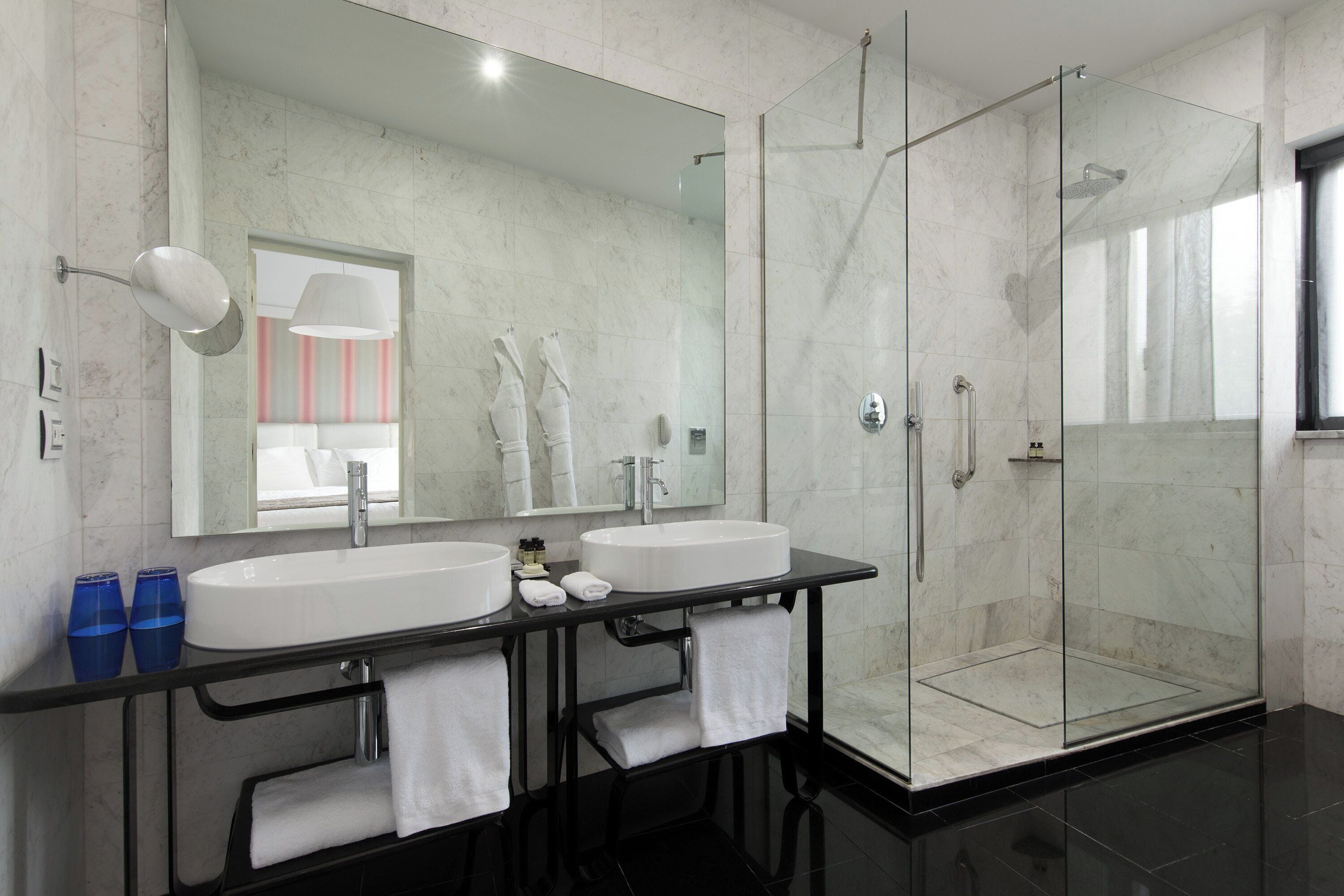 Une salle de bain moderne avec deux lavabos, une douche à l’italienne et un grand miroir.