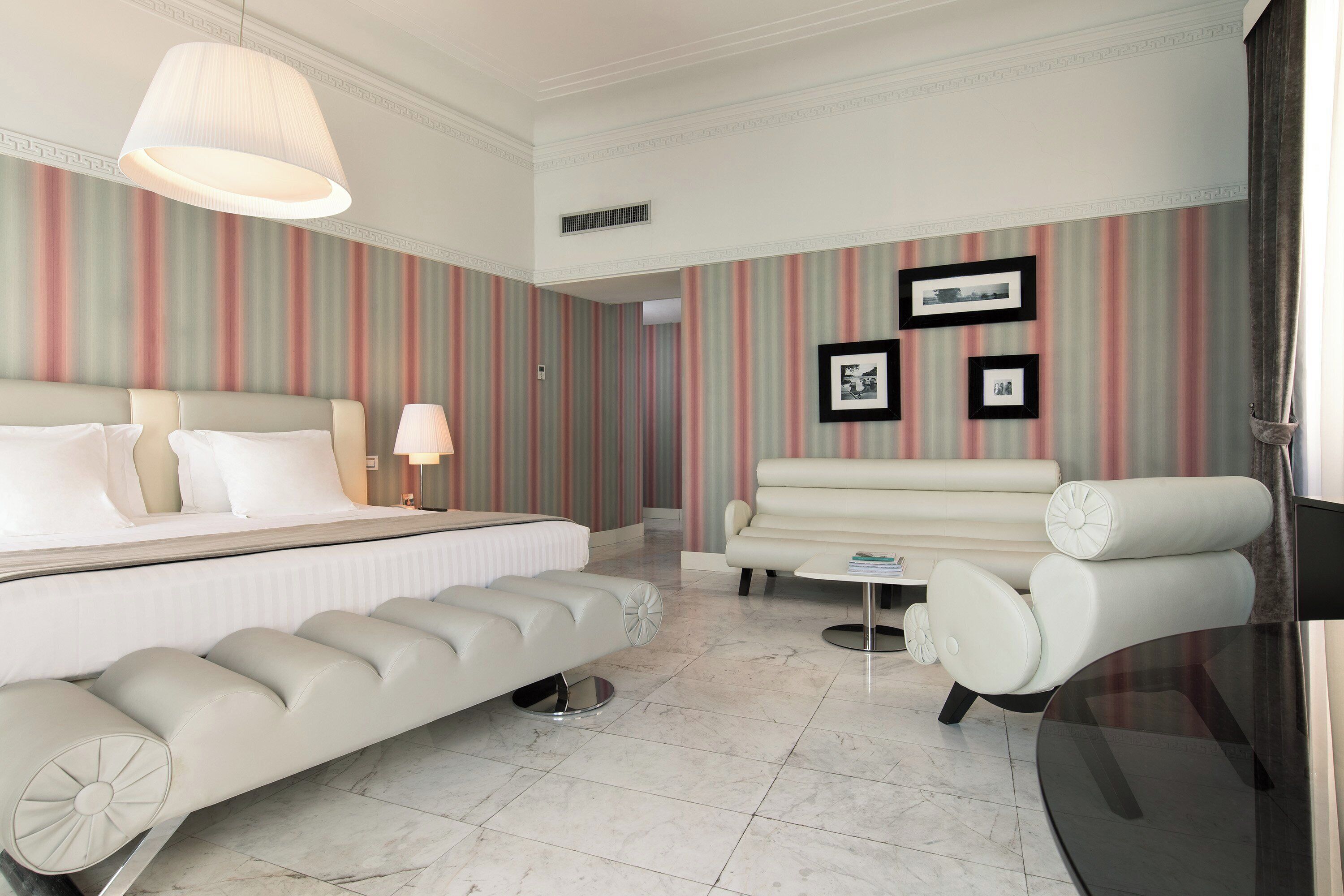 Una habitación de hotel con una cama, un sofá, una silla, un televisor y una lámpara.
