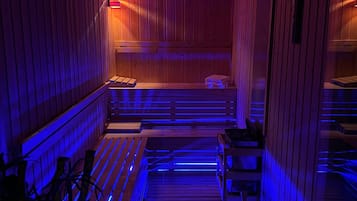 A sauna with wooden walls and benches, a bench with a towel, and a bench with a towel.