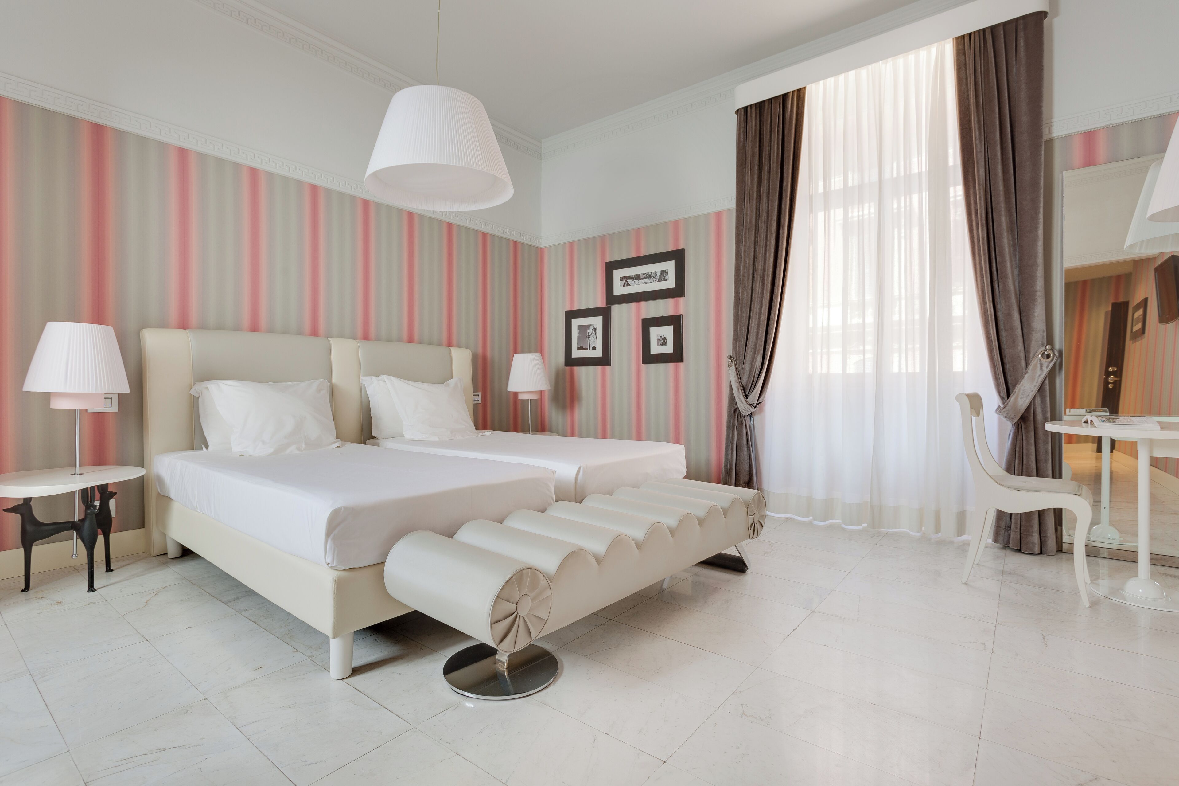 A hotel room with a large bed, two bedside tables, a desk, and a chair.