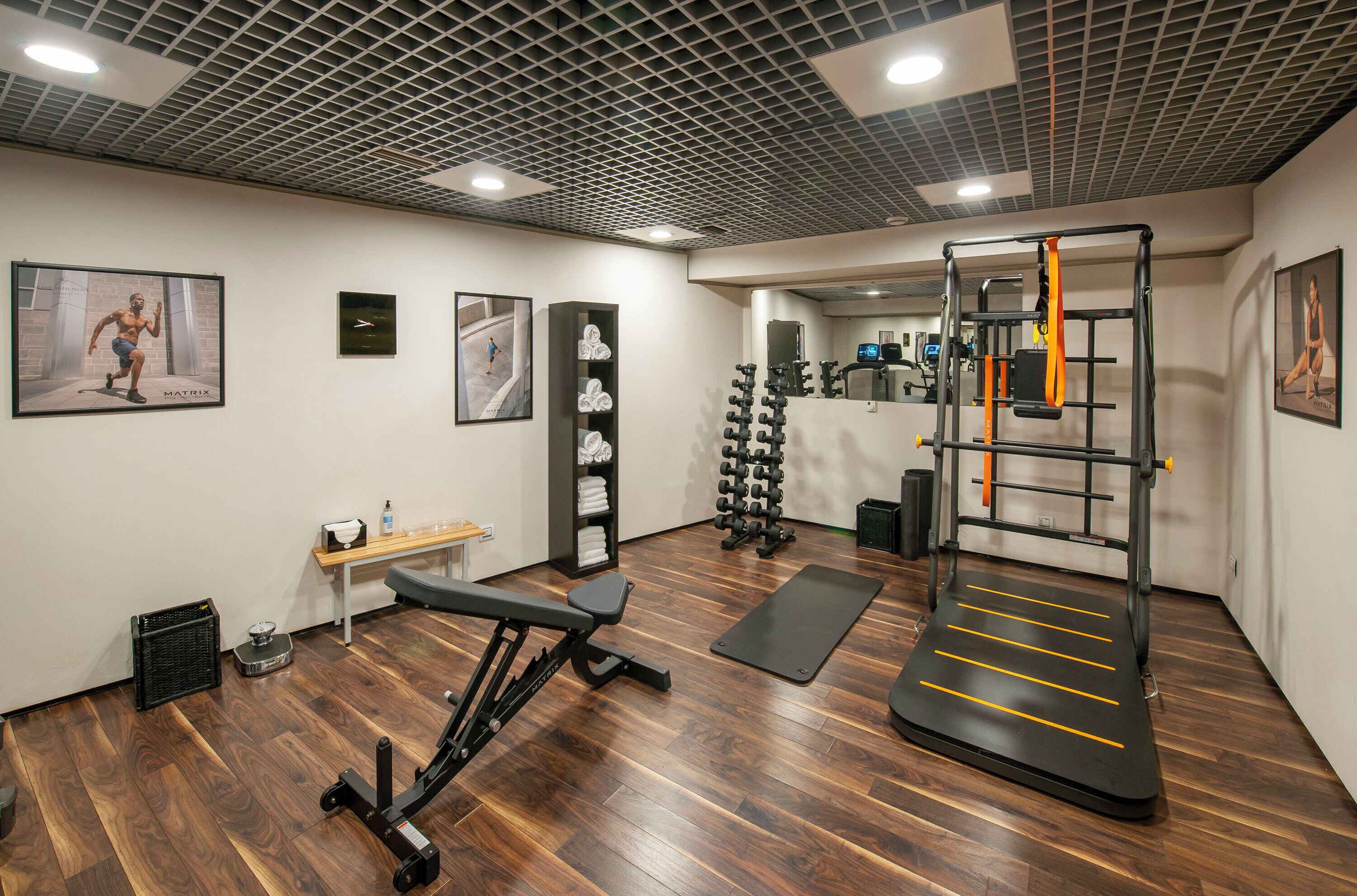 A gym with wooden flooring, exercise equipment, and motivational posters.
