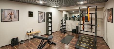 A gym with wooden flooring, exercise equipment, and motivational posters.
