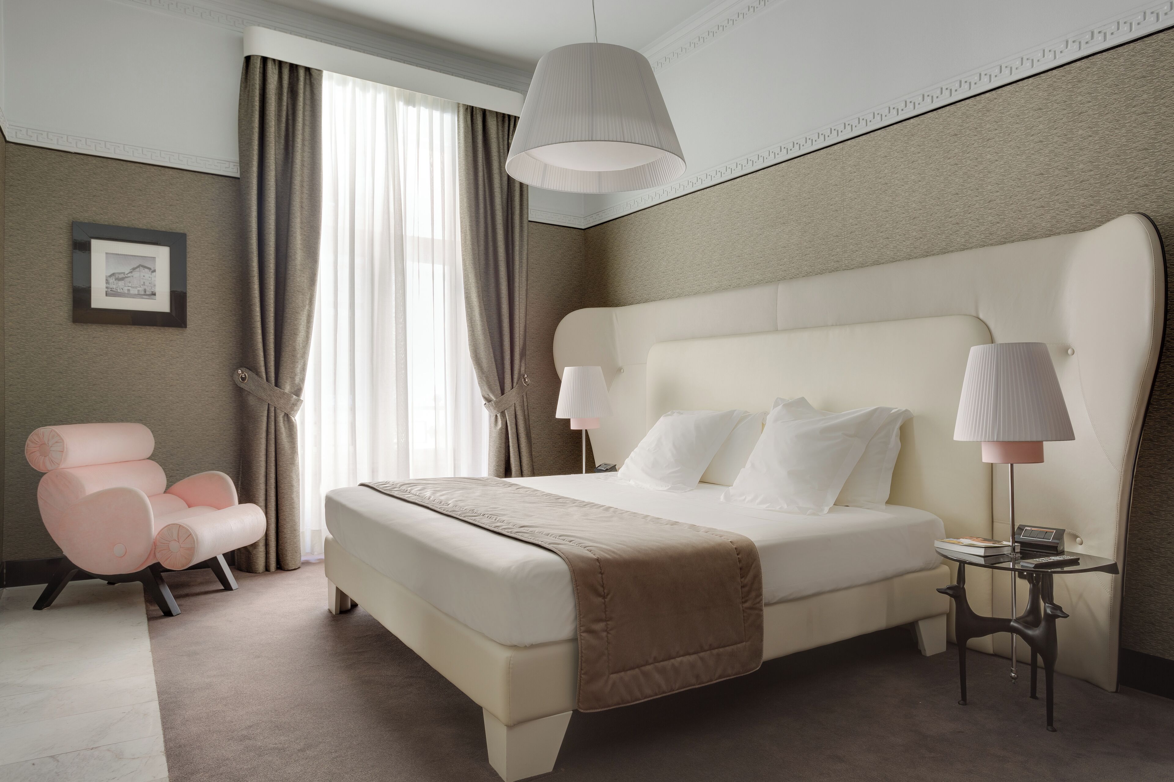 Habitación de hotel con una cama grande, una mesita de noche, una silla y una ventana con cortinas.