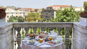 A balcony with a table set for breakfast, overlooking a cityscape with historic buildings. - Grand Hotel Palace Rome (Rome)