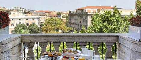Un balcón con una mesa lista para el desayuno, con vistas a una ciudad con edificios históricos.