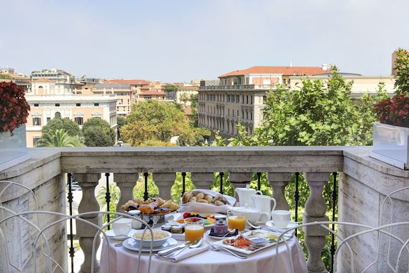 A balcony with a table set for breakfast, overlooking a cityscape with historic buildings.