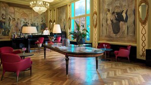 A luxurious room with a bar area, red chairs, a large chandelier, and a painting on the wall. - Grand Hotel Palace Rome (Rome)