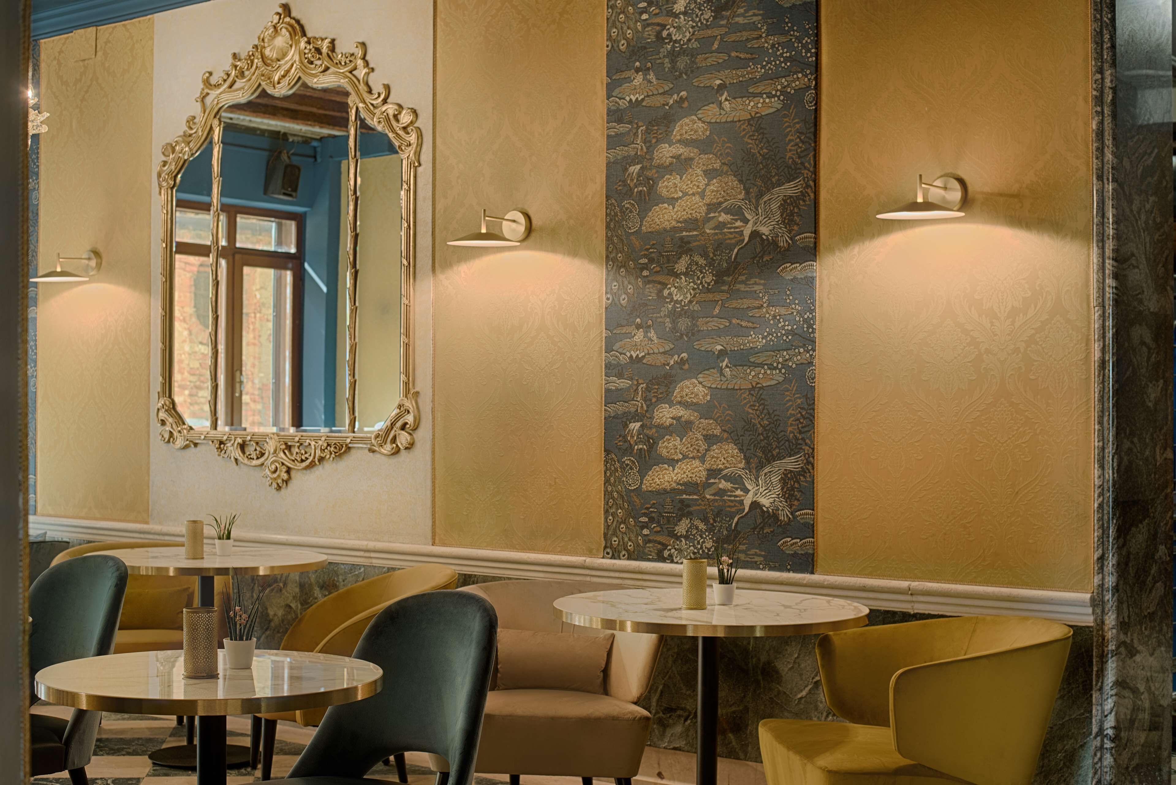 Une pièce avec une table ronde, deux chaises, un miroir et un mur décoré de motifs.
