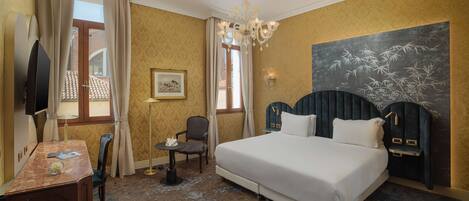 A hotel room with a large bed, a desk, a chair, a television, and a painting on the wall.