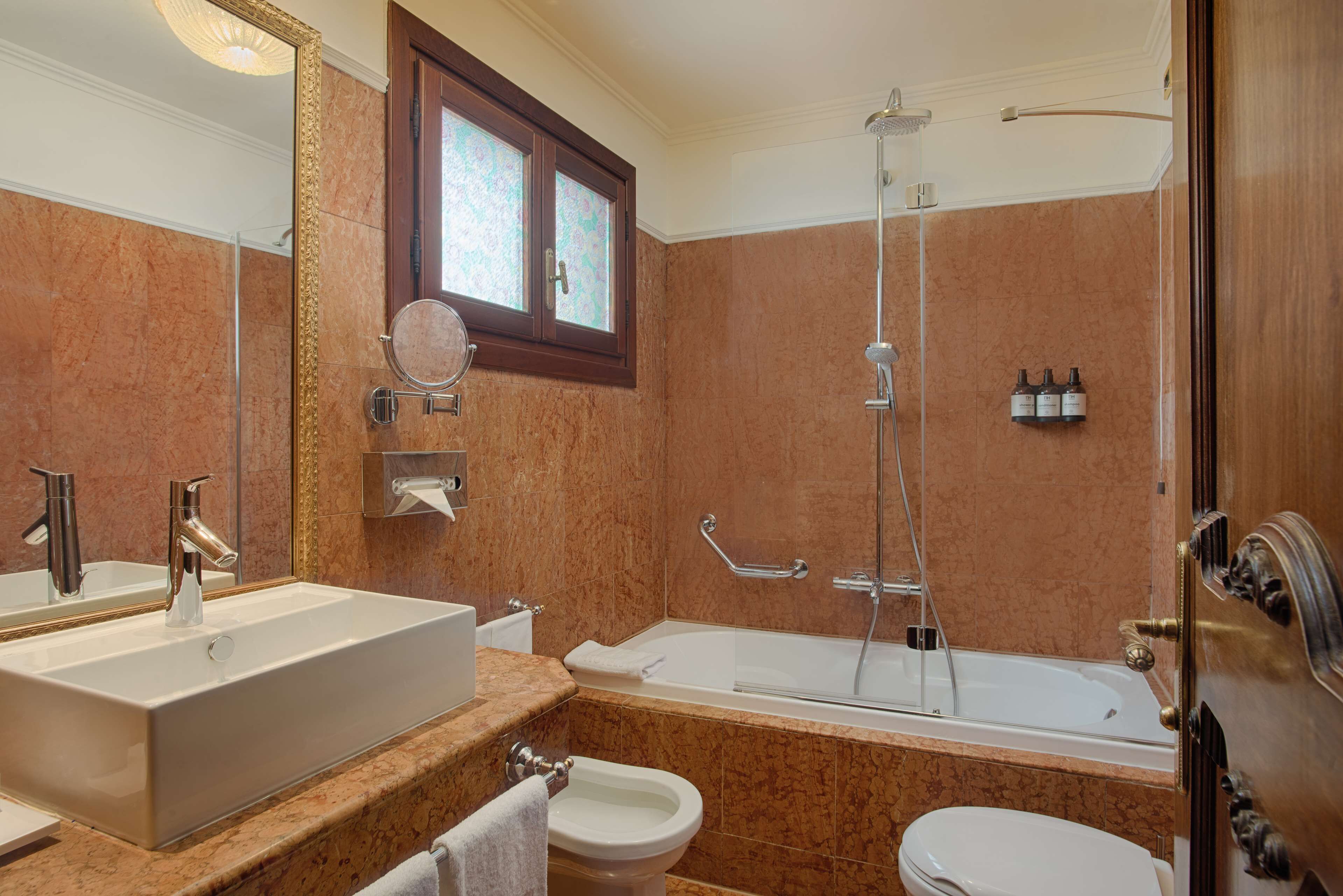 A bathroom with a large sink, a bathtub, a toilet, and a shower.