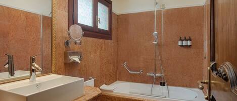 A bathroom with a large sink, a bathtub, a toilet, and a shower.