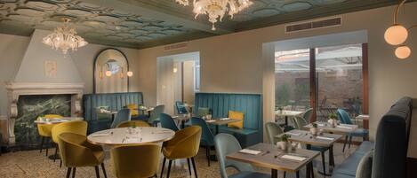 Un restaurant avec des tables rondes, des banquettes bleues et des chaises jaunes.