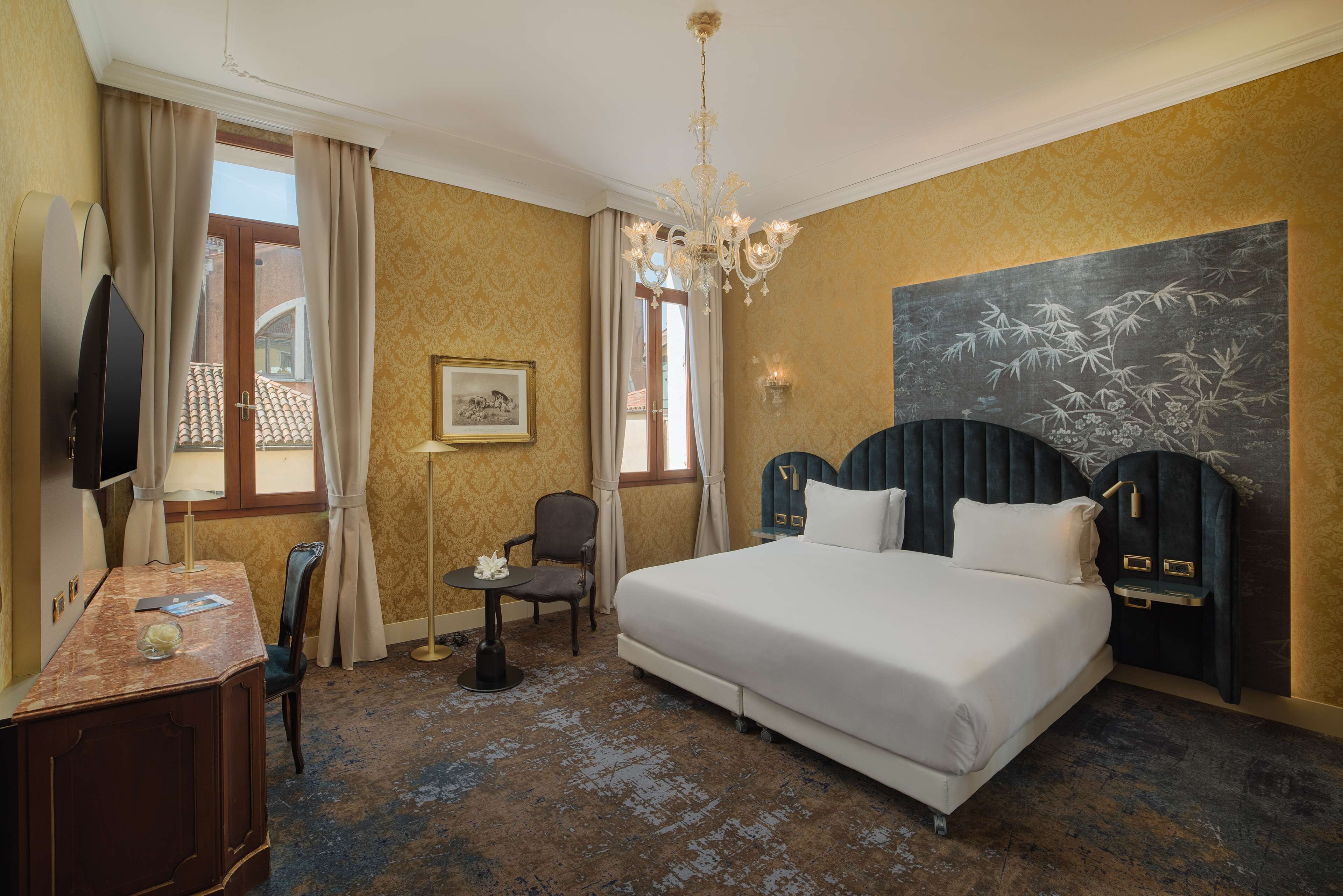 A hotel room with a large bed, a desk with a chair, a television, and a painting on the wall.
