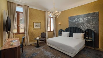 Ein Hotelzimmer mit einem großen Bett, einem Schreibtisch mit Stuhl, einem Fernseher und einem Gemälde an der Wand.