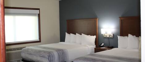 Ett hotellrum med två sängar, ett nattduksbord med en telefon och ett fönster med persienner.