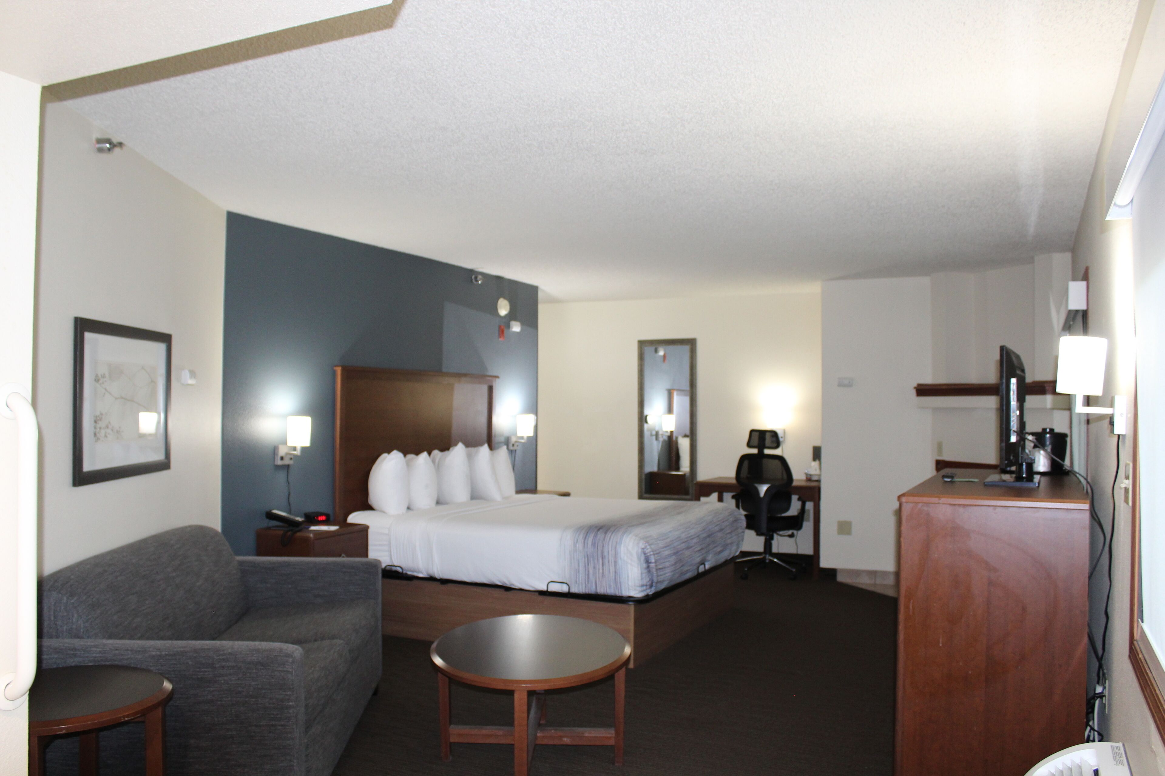 Quarto de hotel com cama, sofá, escrivaninha e cadeira.