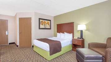 Una habitación de hotel con una cama, una mesita de noche, una lámpara, una silla y una puerta.