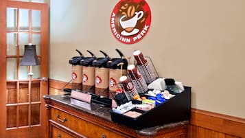 A coffee station with multiple coffee dispensers and a sign for Americinn Perk.