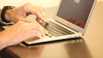 A person typing on a laptop with a visible screen displaying a coffee cup icon.