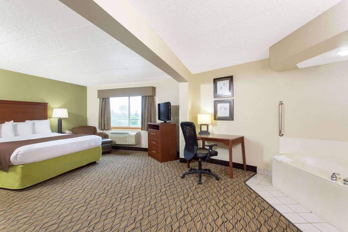 Habitación de hotel con cama, escritorio, silla, televisión, aire acondicionado y bañera.