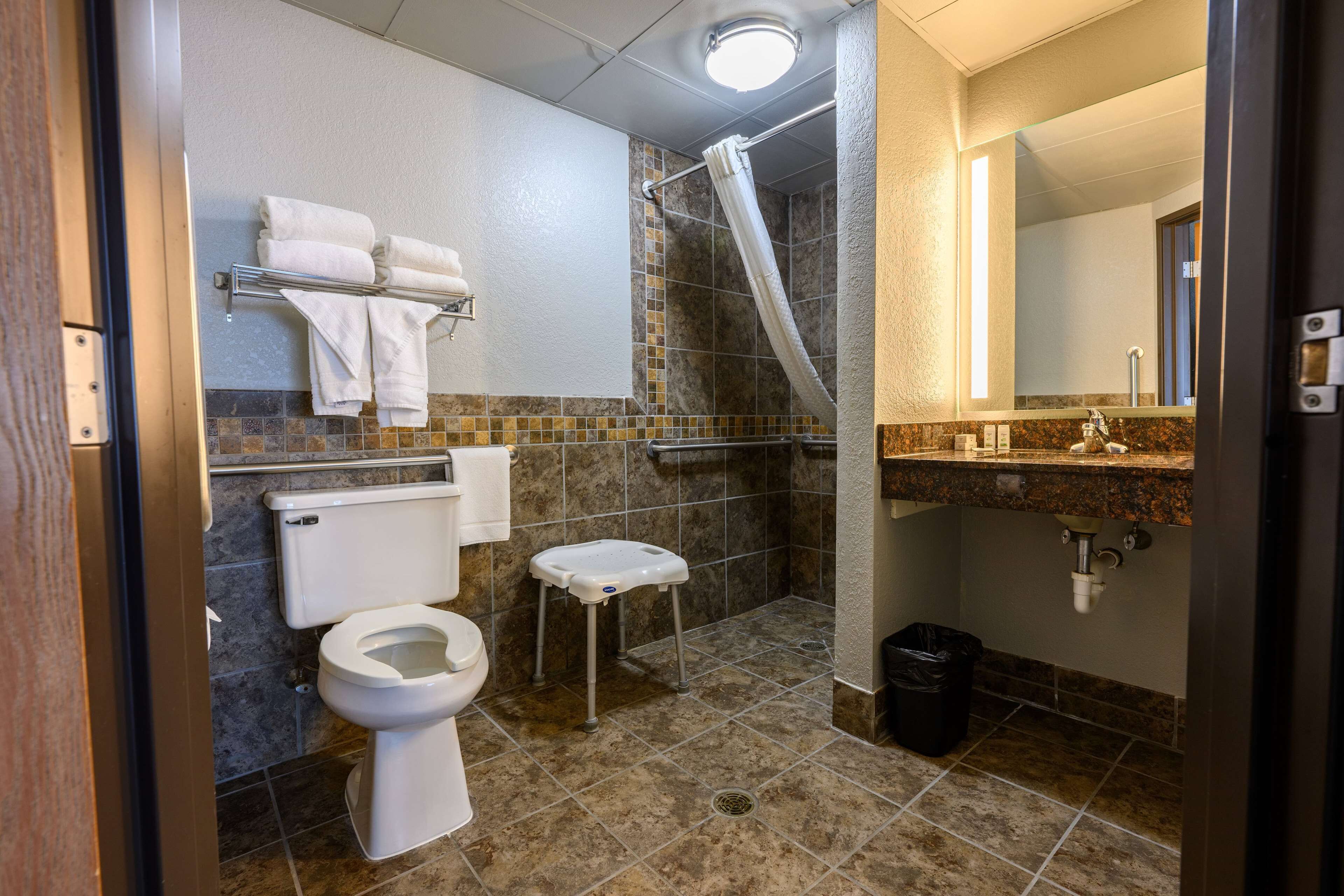 Et badeværelse med toilet, brusebad, håndvask og spejl.