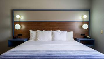 Habitación de hotel con una cama grande, dos mesitas de noche, cabecero de madera y lámparas fijadas a la pared.
