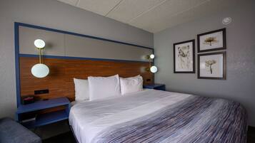 A hotel room with a large bed, a wooden headboard, bedside tables with lamps, and framed artwork on the wall.